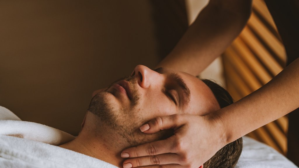 Man receiving facial massage from hands in a spa setting