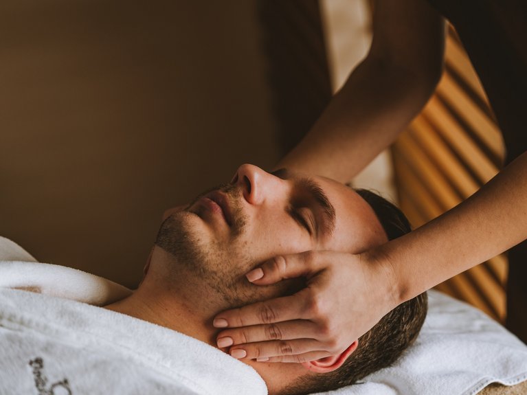 Man receiving facial massage from hands in a spa setting