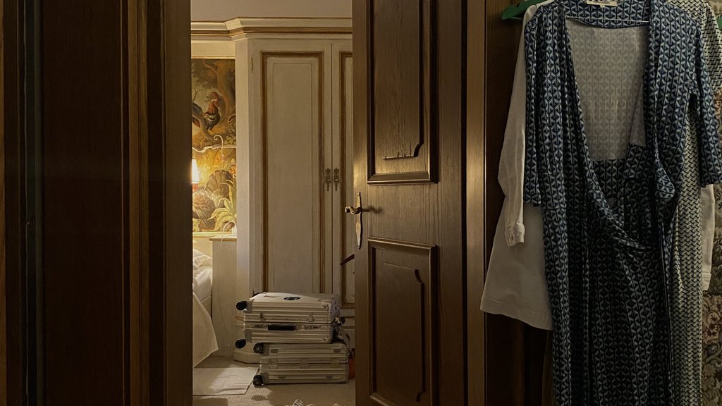 Open door showing a room with stacked suitcases and dresses hanging on the wall