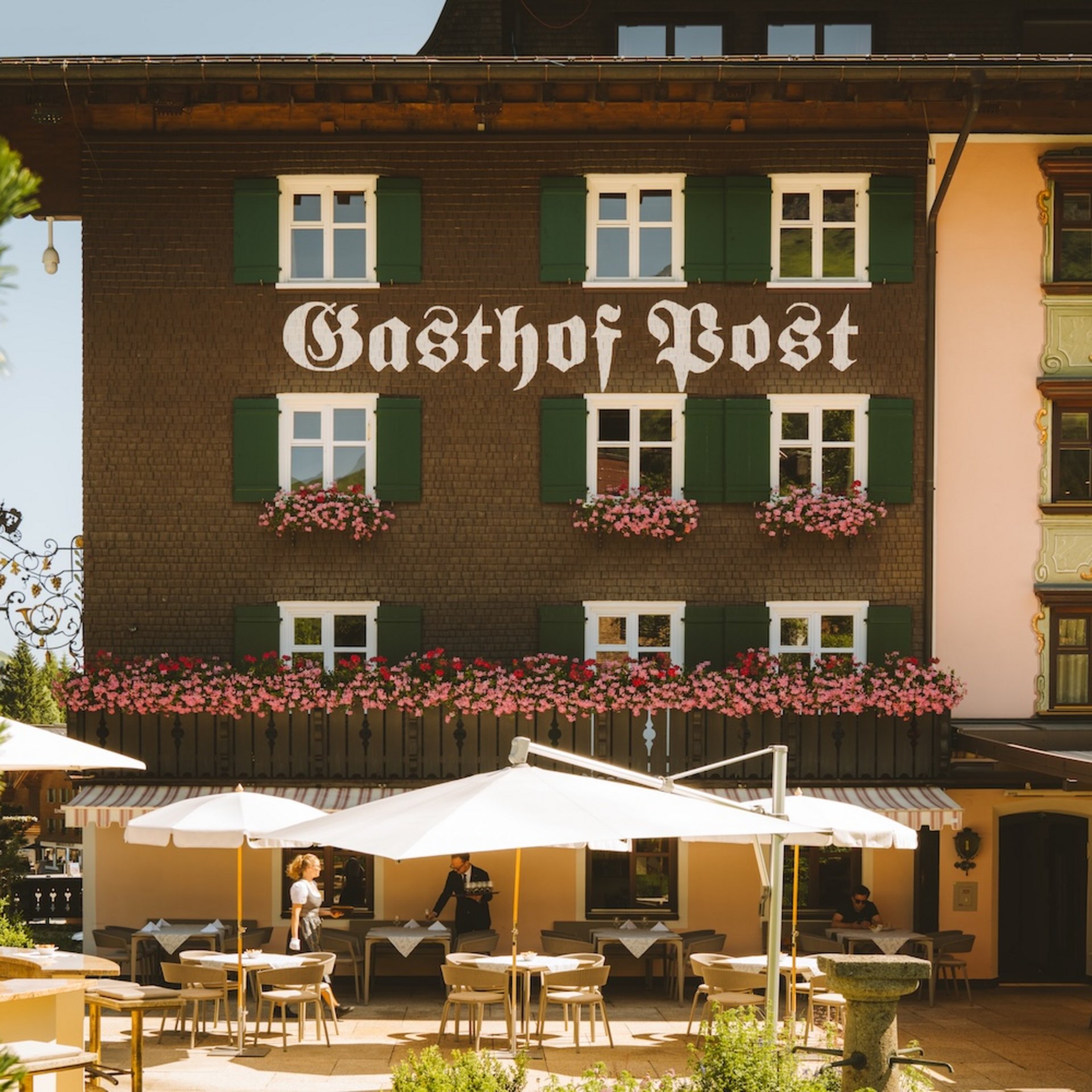 Facade of Gasthof Post with outdoor terrace and white umbrellas