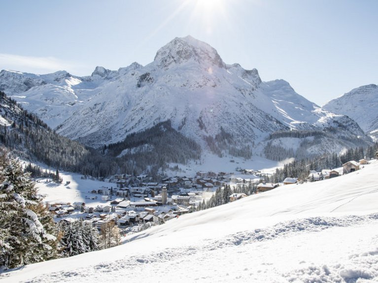 Schneebedeckte Berge und ein Dorf im Tal bei klarem Himmel