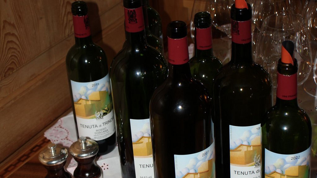 Mehrere Weinflaschen auf einem bestickten Tischtuch mit Gläsern im Hintergrund