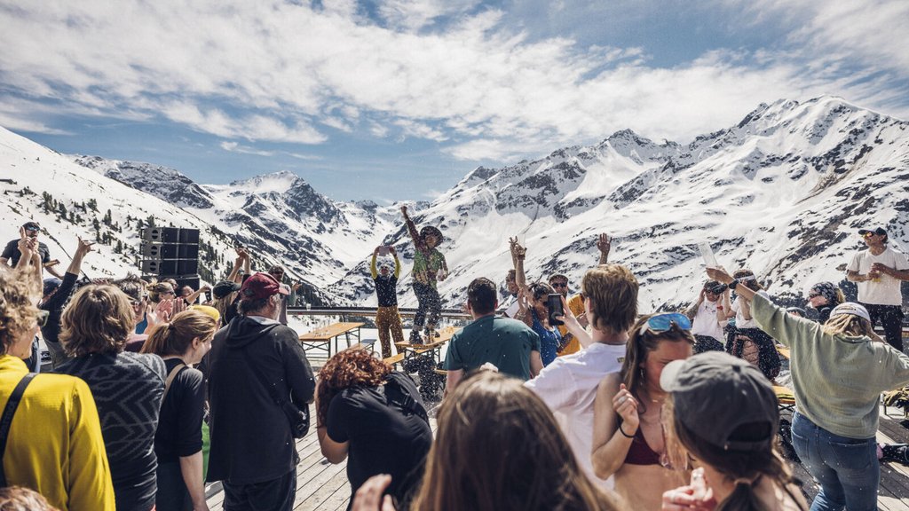 Menschen feiern draußen auf einer Terrasse in schneebedeckten Bergen bei Sonnenschein