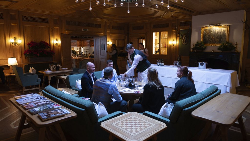Wenn große Weine auf alpine Gastfreundschaft treffen Gäste speisen in einem holzgetäfelten Restaurant, während ein Kellner am Tisch serviert