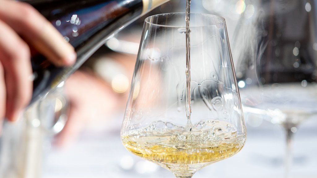 Wenn große Weine auf alpine Gastfreundschaft treffen Weißwein wird in ein Glas eingeschenkt