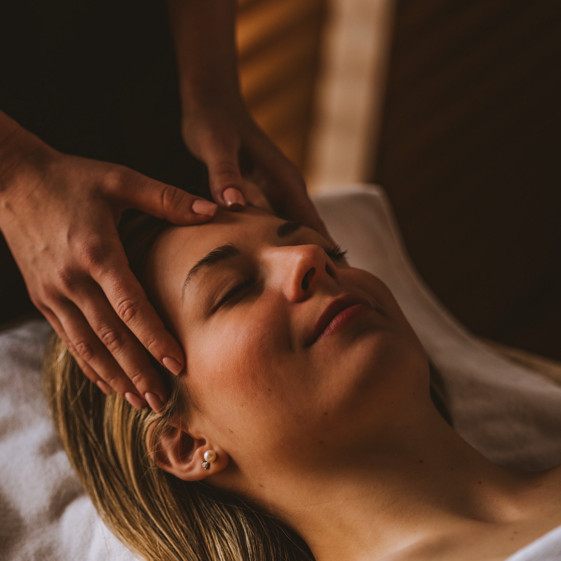 Woman receiving a relaxing facial massage in soft lighting