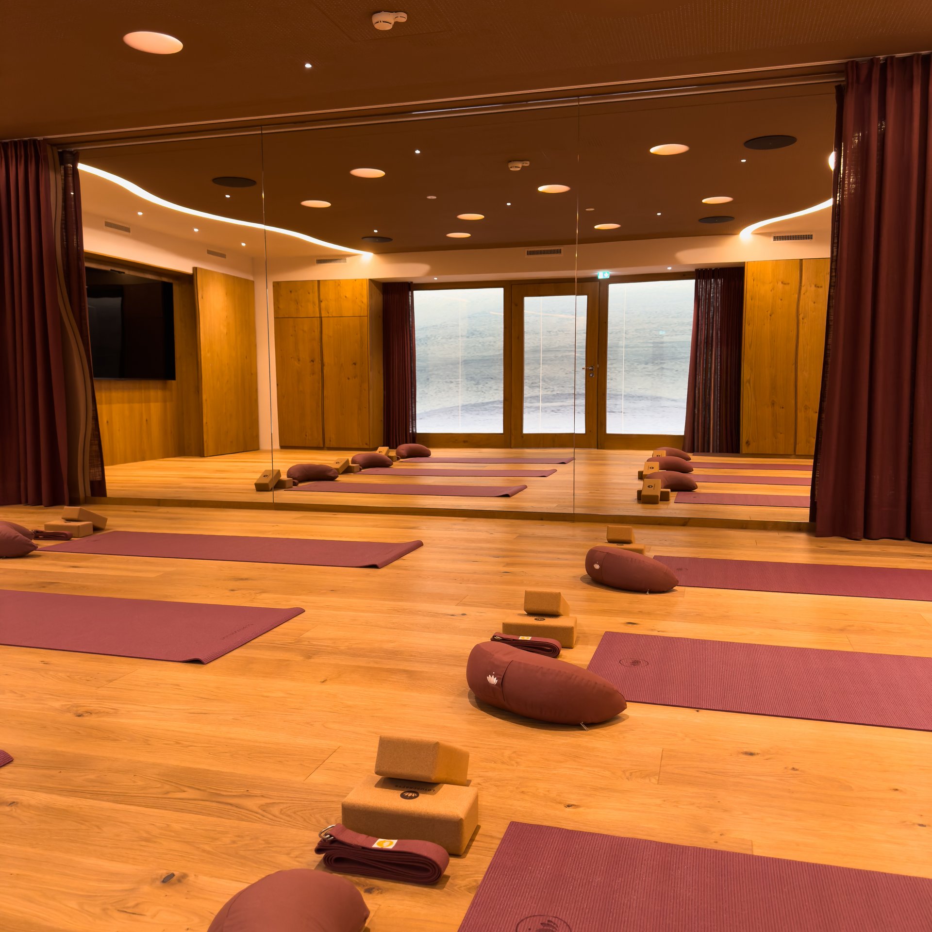 Yogaraum mit lila Matten, Kissen, Blöcken und Holzboden