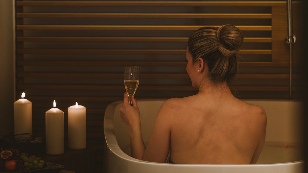 Woman relaxing in bathtub with candles and a glass of wine