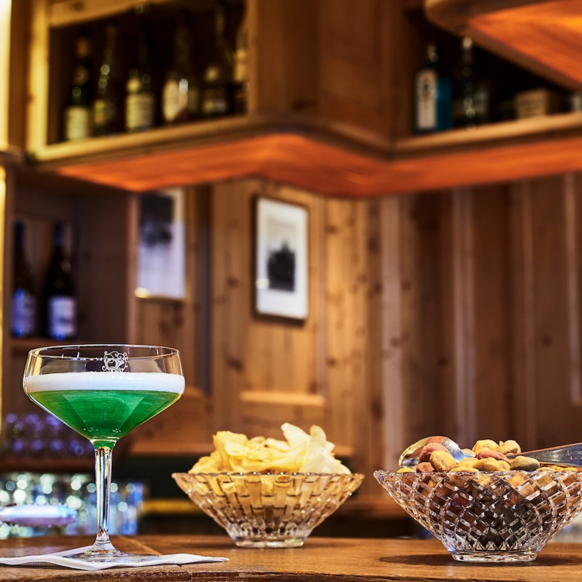 Green beer with chips and nuts at a bar