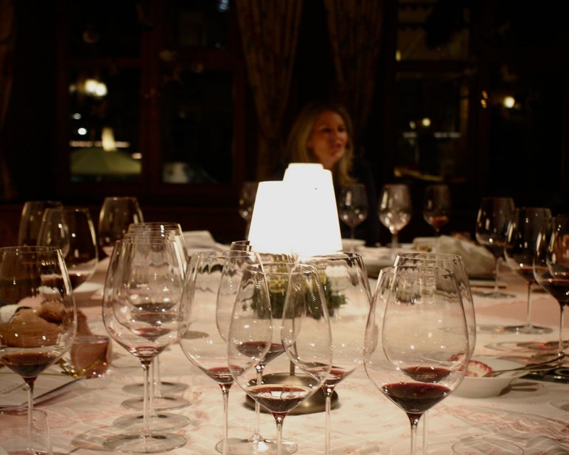 Weingläser mit rotem Wein auf einem gedeckten Tisch bei gedimmtem Licht