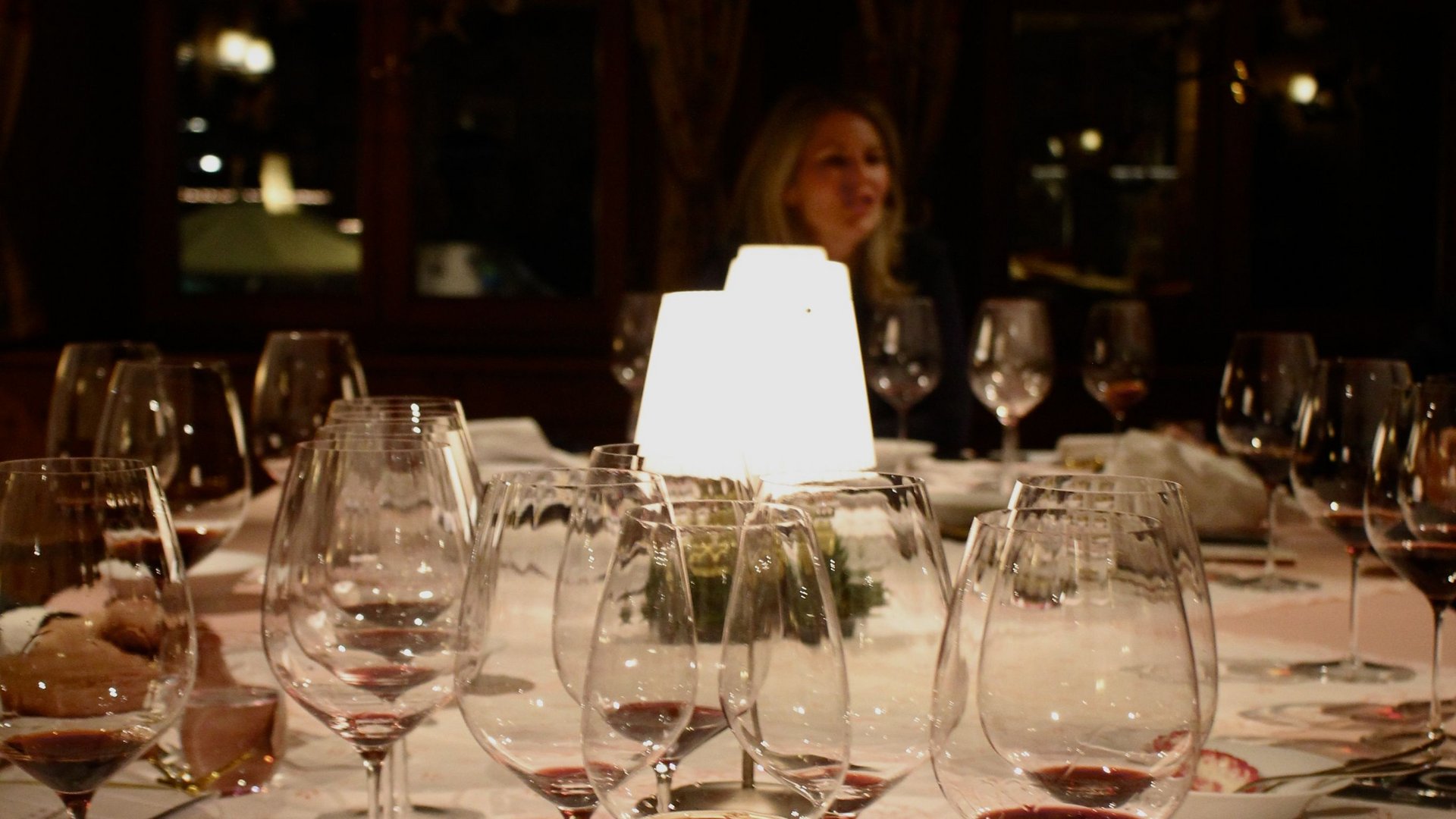 Weingläser mit rotem Wein auf einem gedeckten Tisch bei gedimmtem Licht