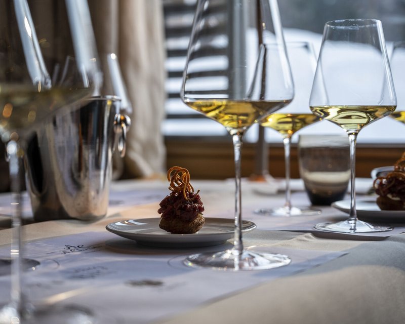 Weingläser mit Weißwein und kleine Häppchen auf einem gedeckten Tisch