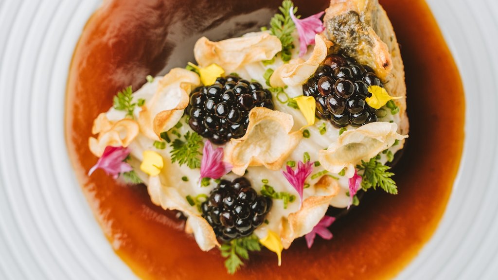 Indulge at Hotel Post Lech at the Arlberg | Alpine Luxury & Culinary Excellence Gourmet poultry dish with sauce and edible flowers on white plate