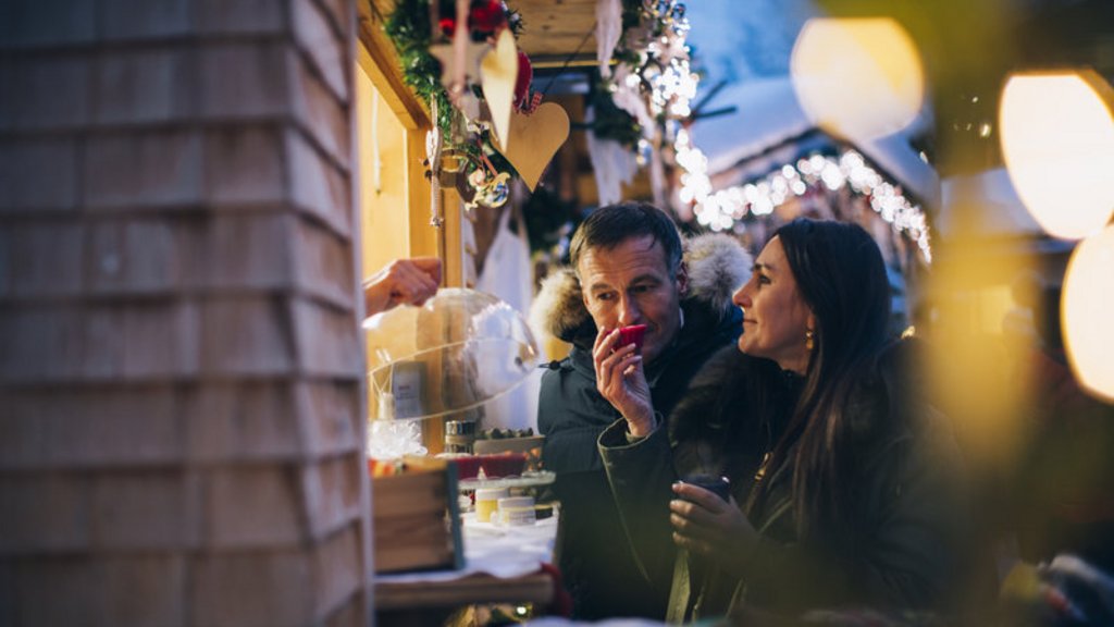Adventzauber Paar genießt Getränke an einem festlich dekorierten Marktstand im Freien