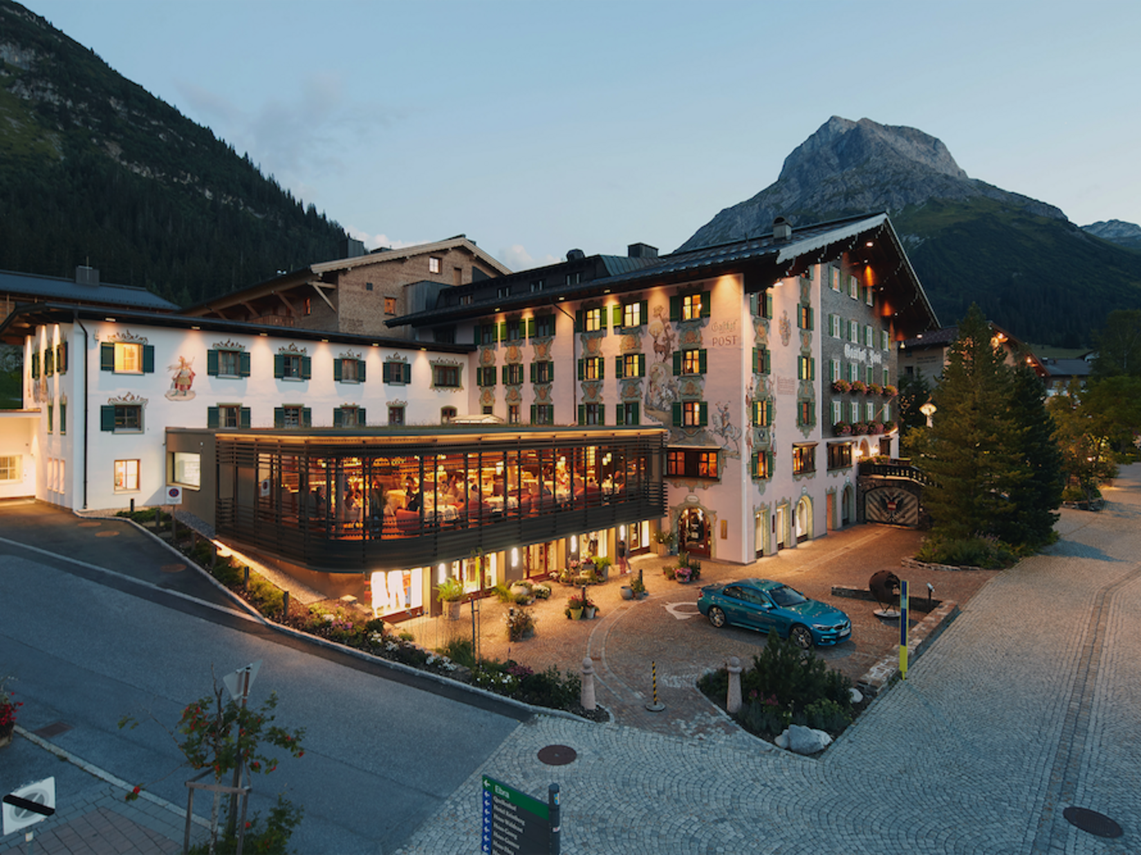 Hotel building with lit restaurant and mountain backdrop at dusk