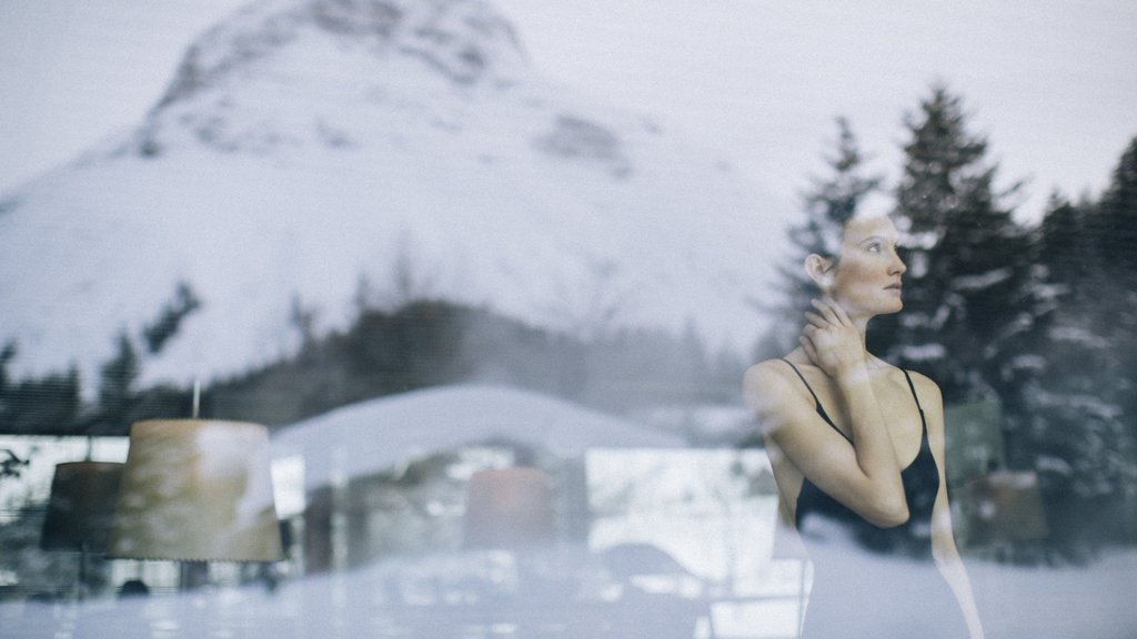 Unter 35 Frau in Badeanzug reflektiert durch Fenster mit Berg und Bäumen im Hintergrund