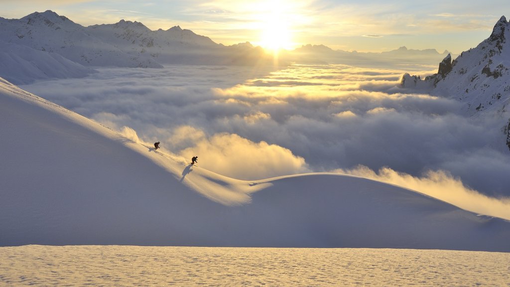 Ski Genuss Zwei Skifahrer fahren bei Sonnenaufgang auf verschneitem Berghang über Wolkenmeer