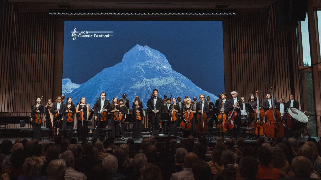 Orchester auf Bühne beim Lech Classic Festival vor Bergkulisse und Publikum