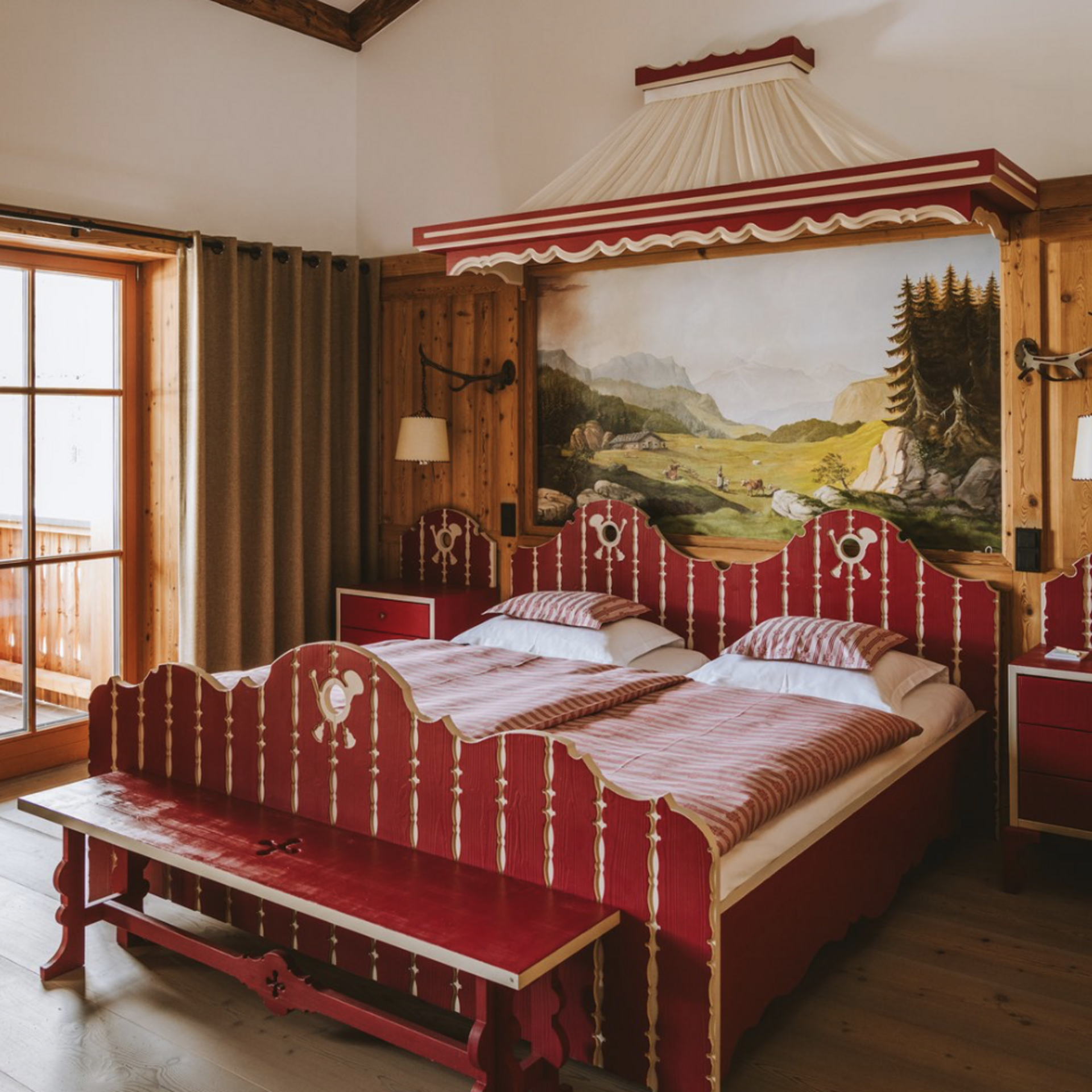 Rustikales Schlafzimmer mit rotem Doppelbett, Holzvertäfelung und Landschaftsgemälde