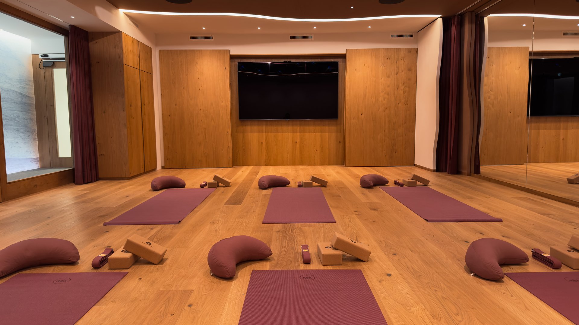 Moderner Yogaraum mit lila Matten, Kissen und Holzblöcken auf Holzboden