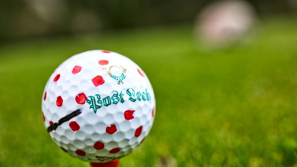 Golf Unlimited Golfball mit roten Punkten auf rotem Abschlag auf grünem Rasen