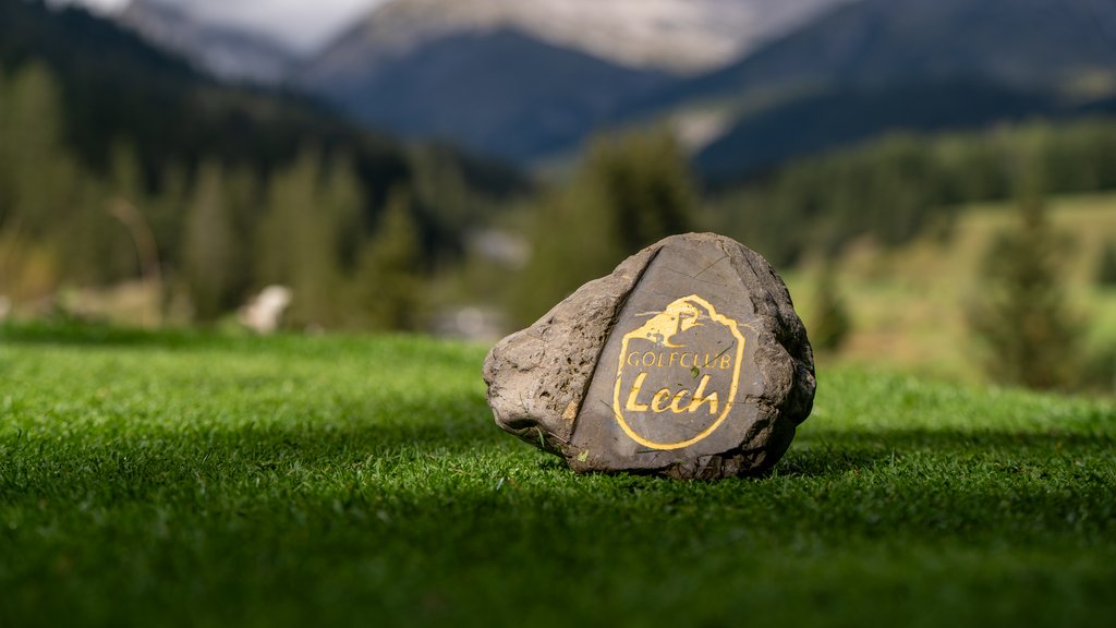 Golfclub Lech Logo auf Stein im Gras mit Bergen im Hintergrund