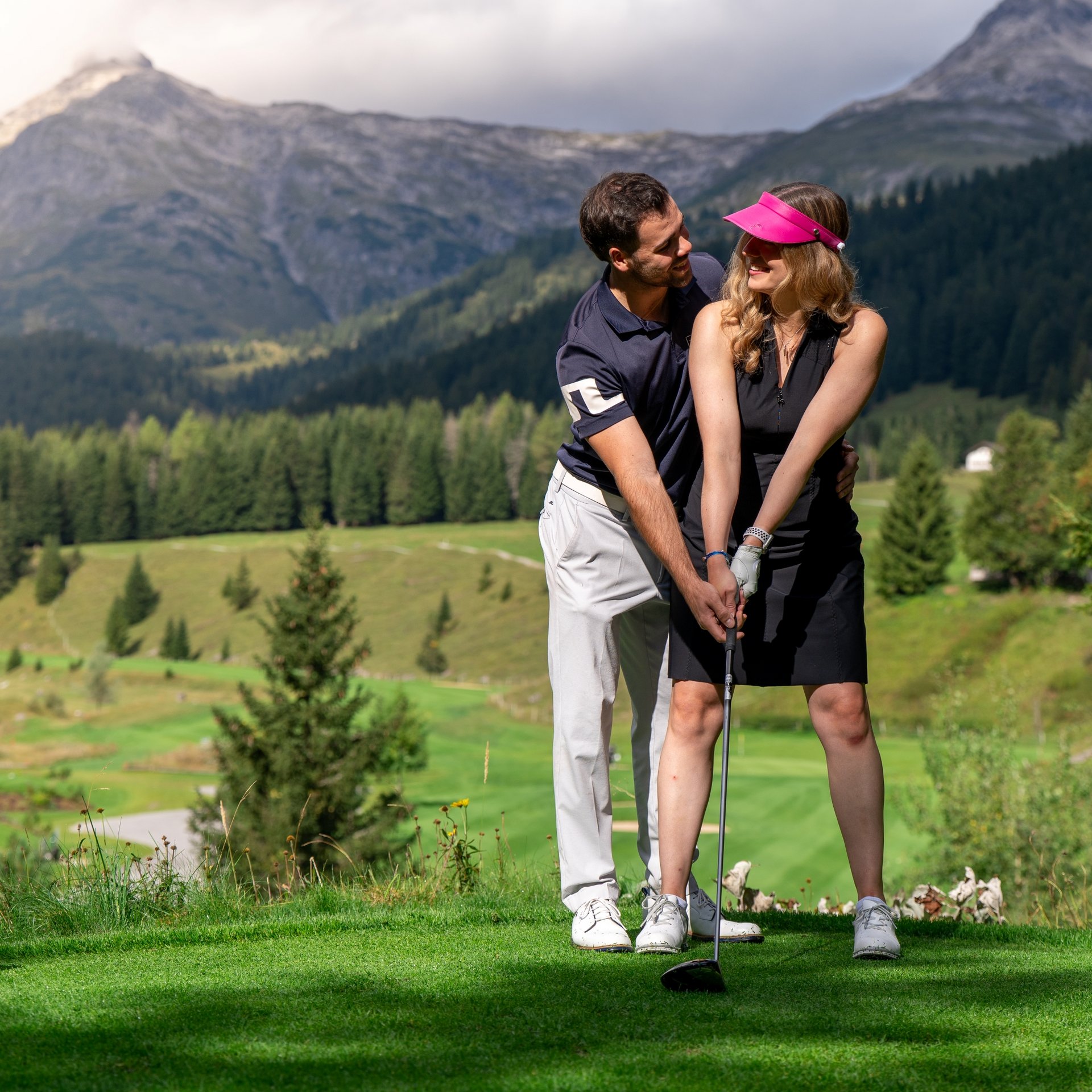 Membership im Golfclub Lech Paar spielt Golf vor Berglandschaft mit grünen Wiesen und Bäumen