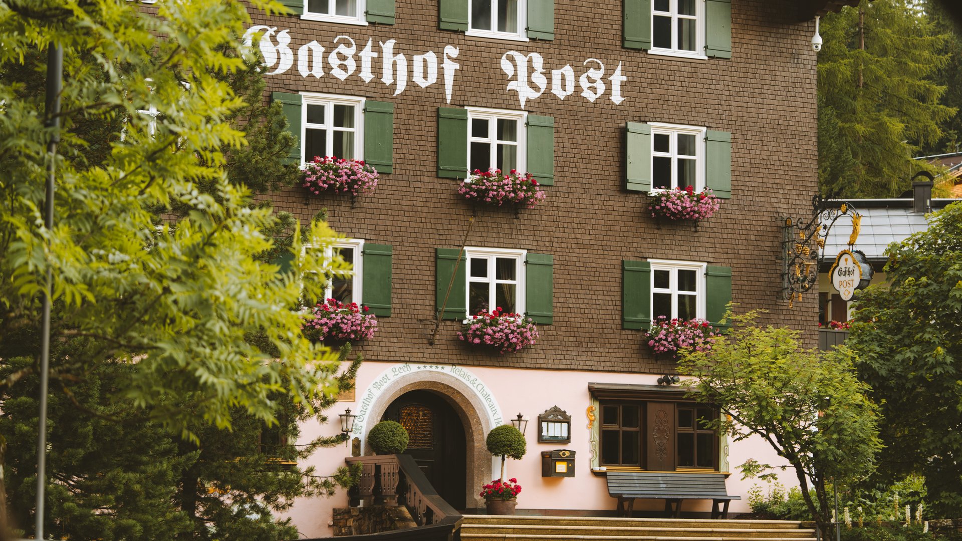 Facade of Gasthof Post with green shutters and flower pots at windows