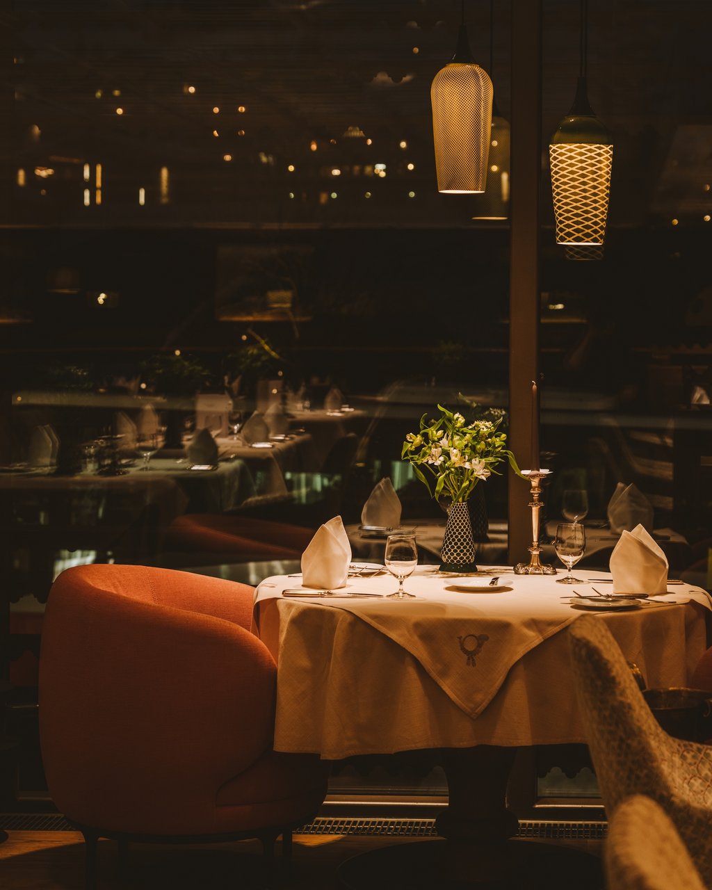 Adventzauber Eleganter gedeckter Tisch mit Blumen und Kerze in einem gemütlichen Restaurant bei Nacht