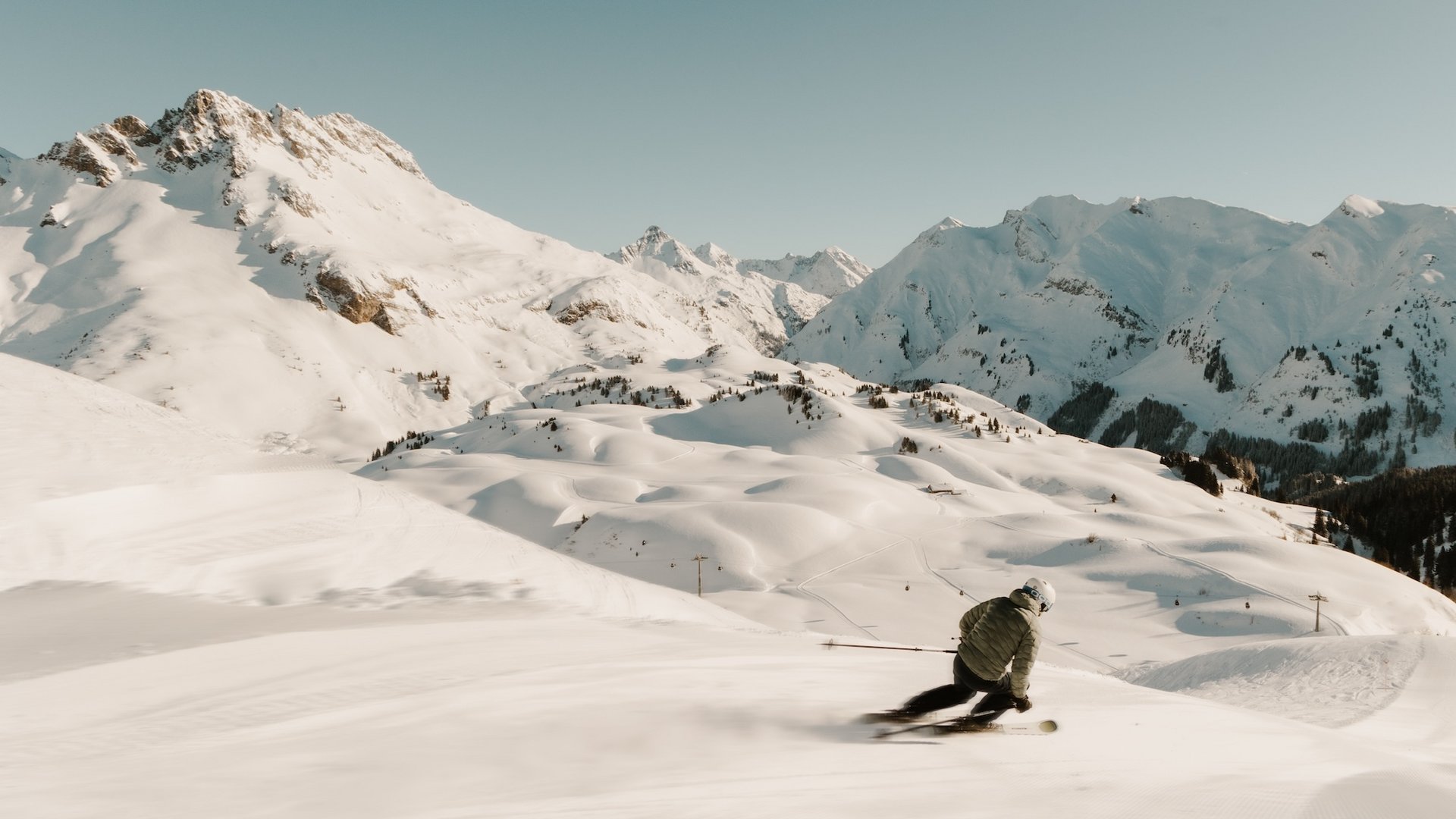 Skier skiing down snowy slope in the Alps under clear sky