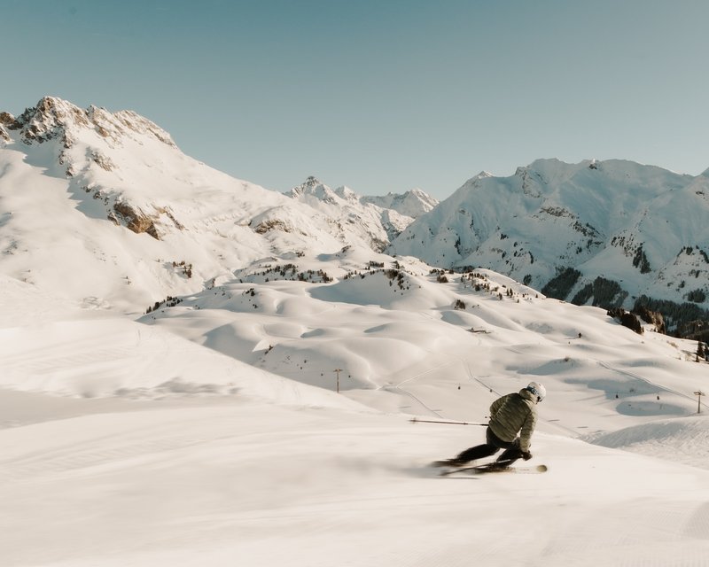 Skier skiing down snowy slope in the Alps under clear sky