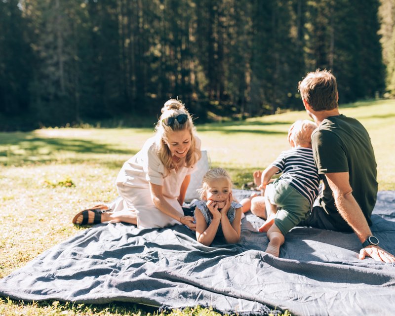 Neues aus der Post Familie mit zwei Kindern entspannt auf einer Decke im sonnigen Park
