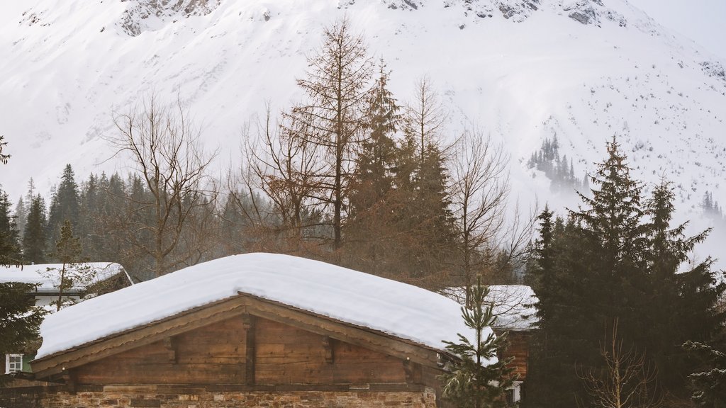 Frühlingsskilauf Person im Außenpool vor schneebedecktem Berg und Holzhütte