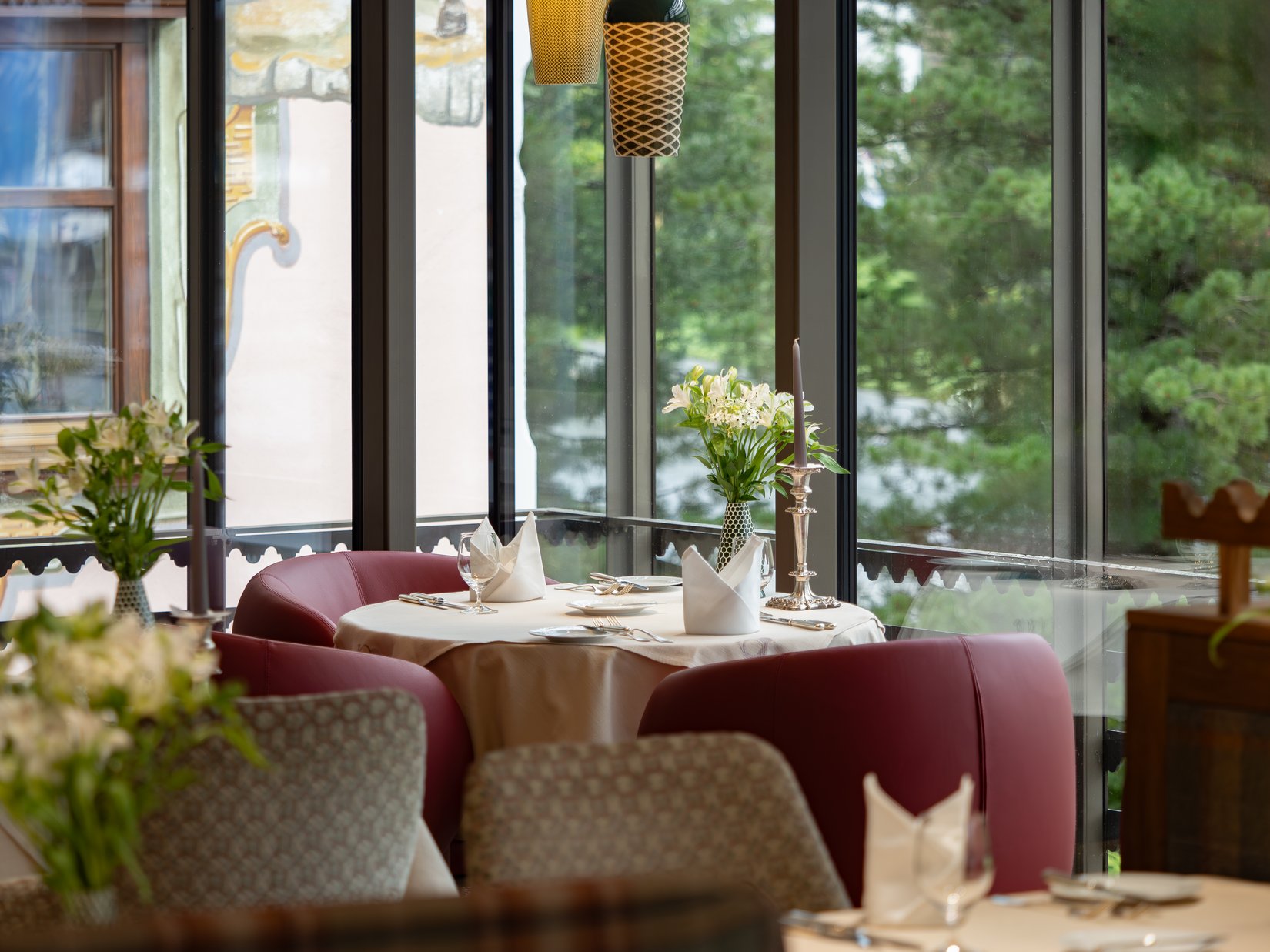 Elegant restaurant table with flowers, candle, and red seating area