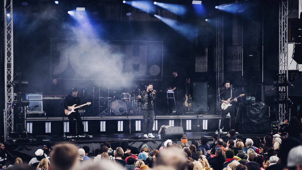 Live-Konzert mit Sänger und Gitarristen vor großem Publikum und Bühnenbeleuchtung