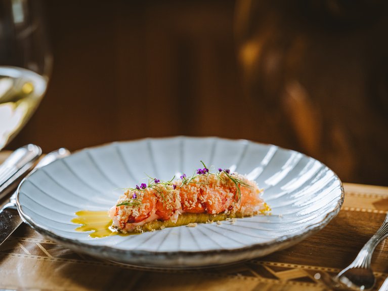 Delicately plated shrimp with sauce and edible flowers on a white plate