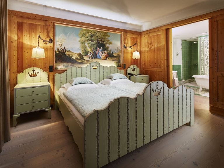 Gemütliches, holzgetäfeltes Schlafzimmer mit zwei Betten und Badezimmer in grün