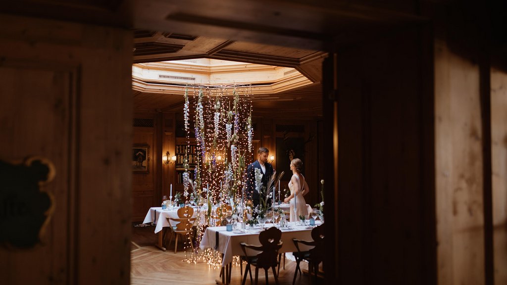 Bride and groom at wedding table with string lights in cozy wooden room