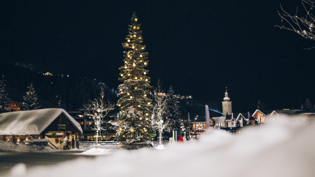 Adventzauber Beleuchteter Weihnachtsbaum in verschneitem Dorf bei Nacht