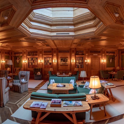 Luxurious wood-paneled room with skylight, bookshelves, and cozy seating areas