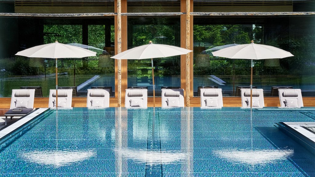 Swimming pool with white umbrellas and lounge chairs in front of wooden windows