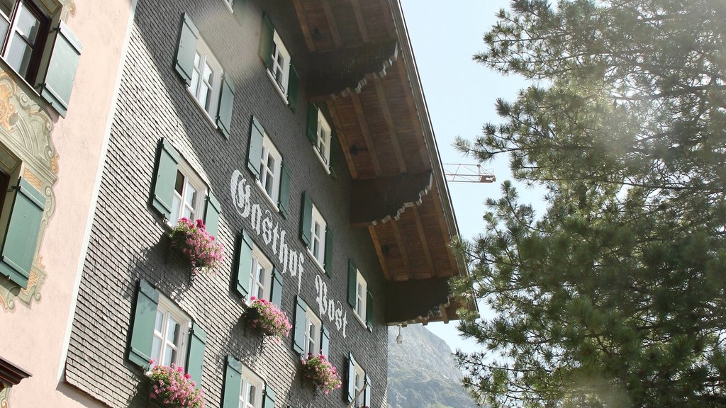 Guesthouse with flower decorations and sunshine next to a tree in the mountains